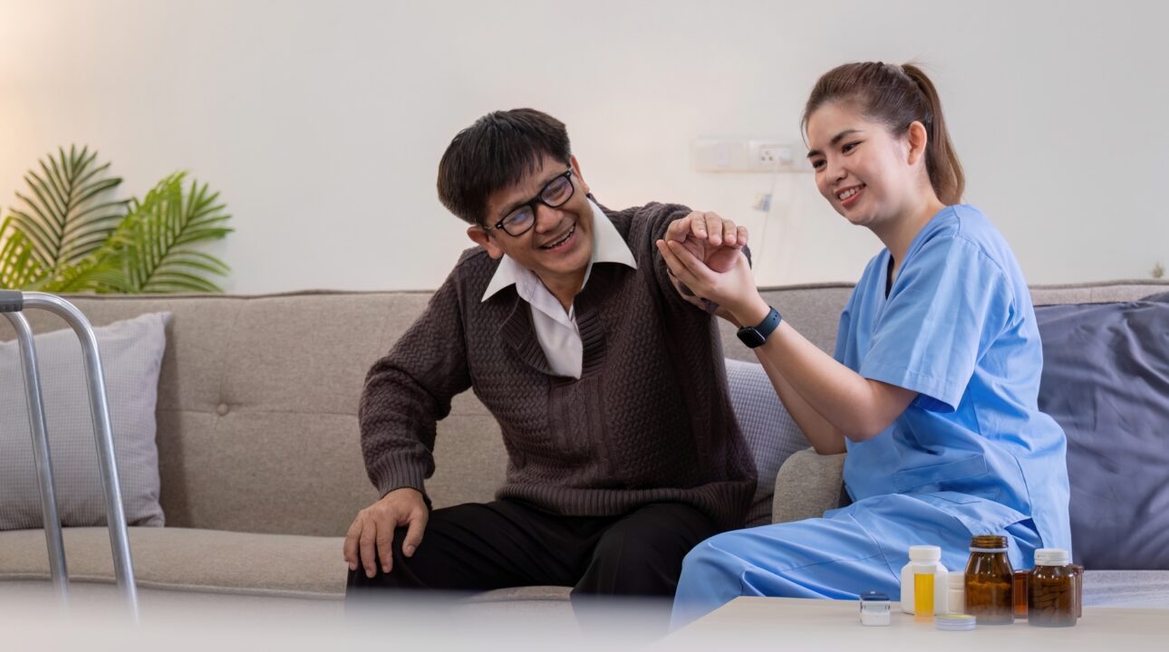 Home Services In Dubai 23 Caregiver Assisting Elderly Man with Physical Therapy at Home, Smiling and Engaging in